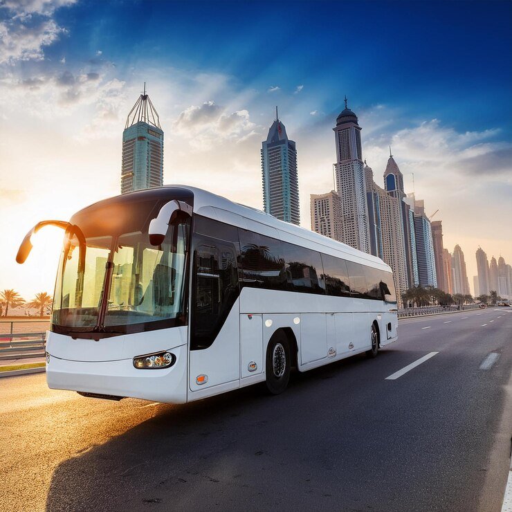 White tour bus driving on an open highway with a clear blue sky and desert landscape in the background, promoting bus rental in Umm Al Quwain for scenic group travel.